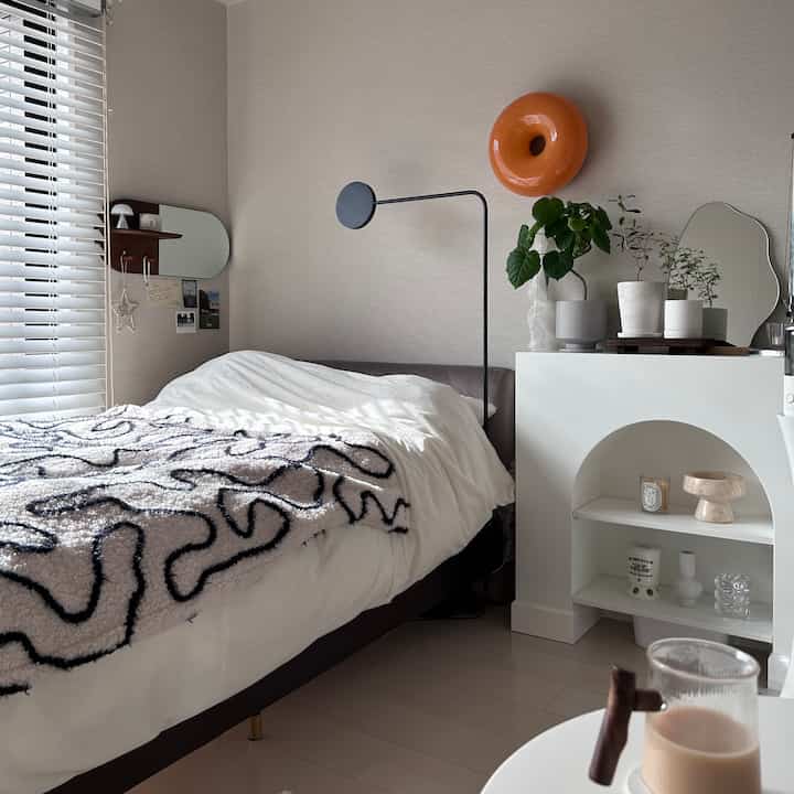 ホワイトとブラウンの色調が特徴の寝室、快適なベッドと観葉植物が配置されたモダンでナチュラルな印象的な空間