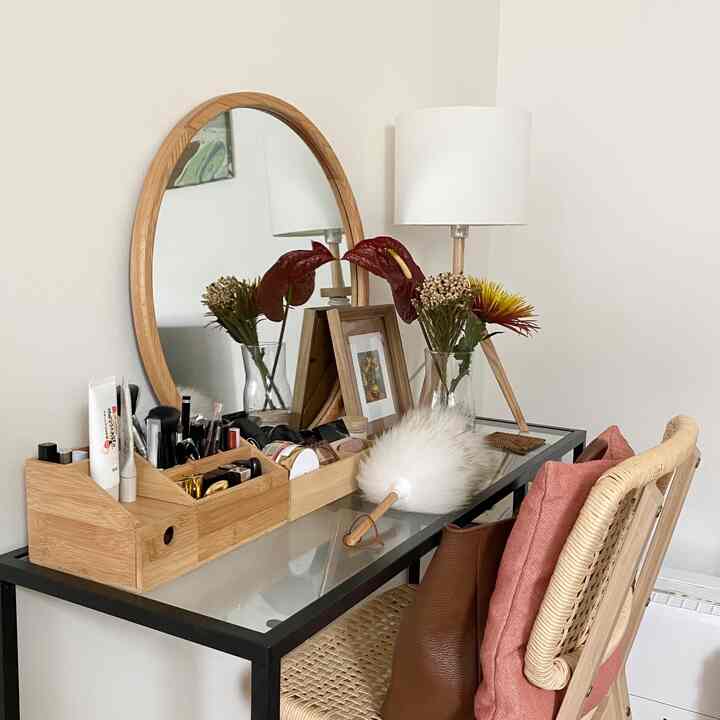 ナチュラルなブラウンとホワイト調のドレッサーとデスクが配置され、花瓶とフロアランプが調和した印象的な作業スペース