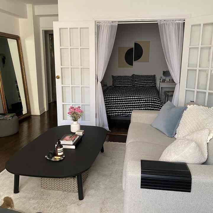White-toned single household living space featuring beige sofa and black coffee table in a minimal interior