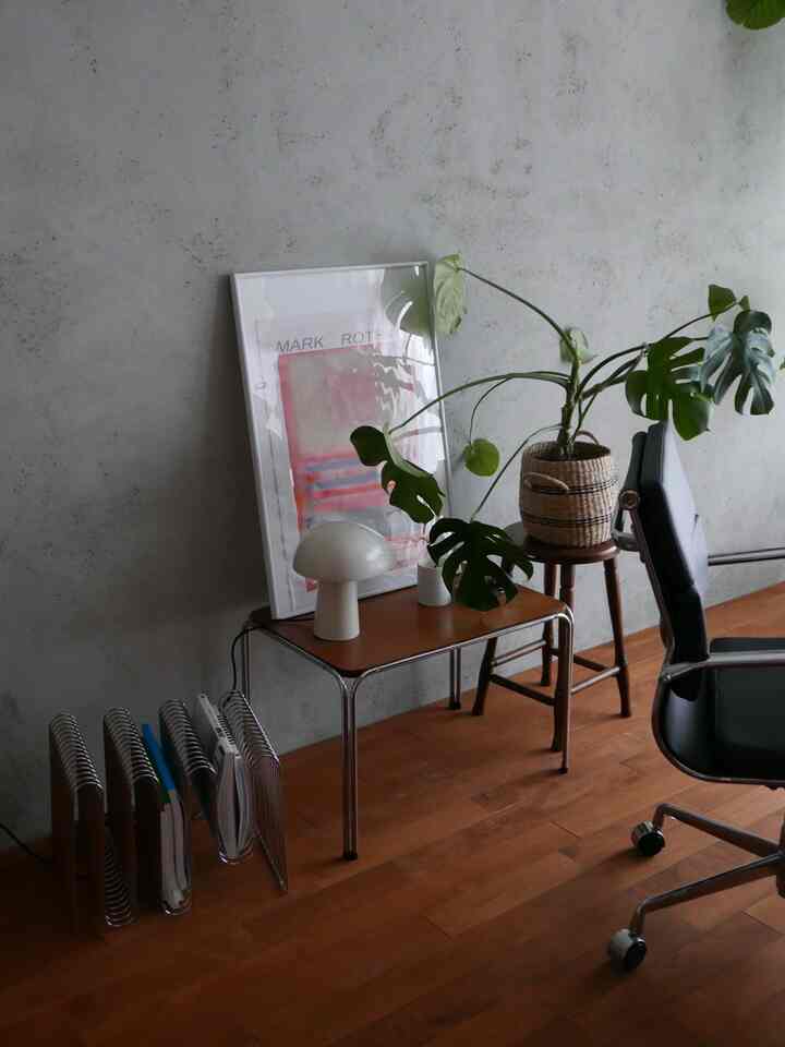 白い壁と木目調の床のリビング、コンソールテーブルにテーブルランプと植物が配置された印象的なミッドセンチュリーモダンのインテリア