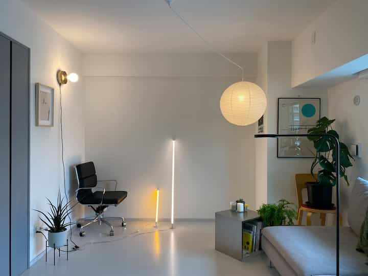 白と黒のモダンなリビング、丸いペンダントライトと植物が配置されたシンプルで自然な雰囲気のインテリア