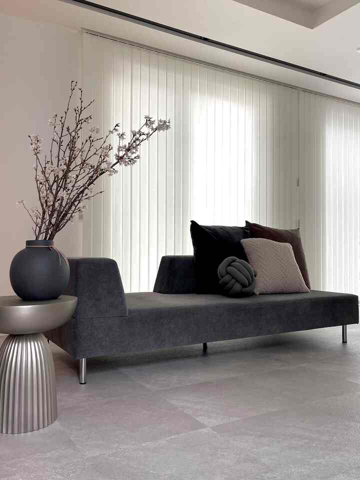 グレーとベージュの色調のリビング、ジャパンディスタイルのソファと花瓶のあるサイドテーブルが配置された印象的な空間