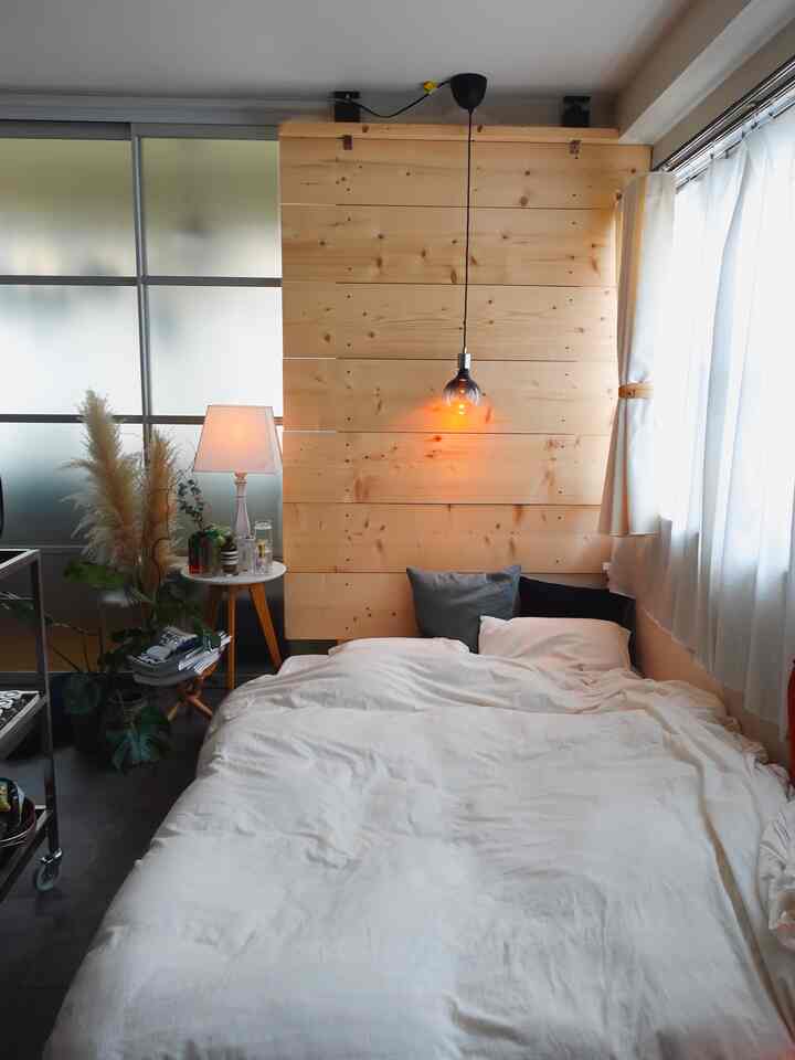 ホワイトと木目調の調和が美しい寝室で、ベッドとペンダントライトが落ち着いた雰囲気を演出しているインテリア