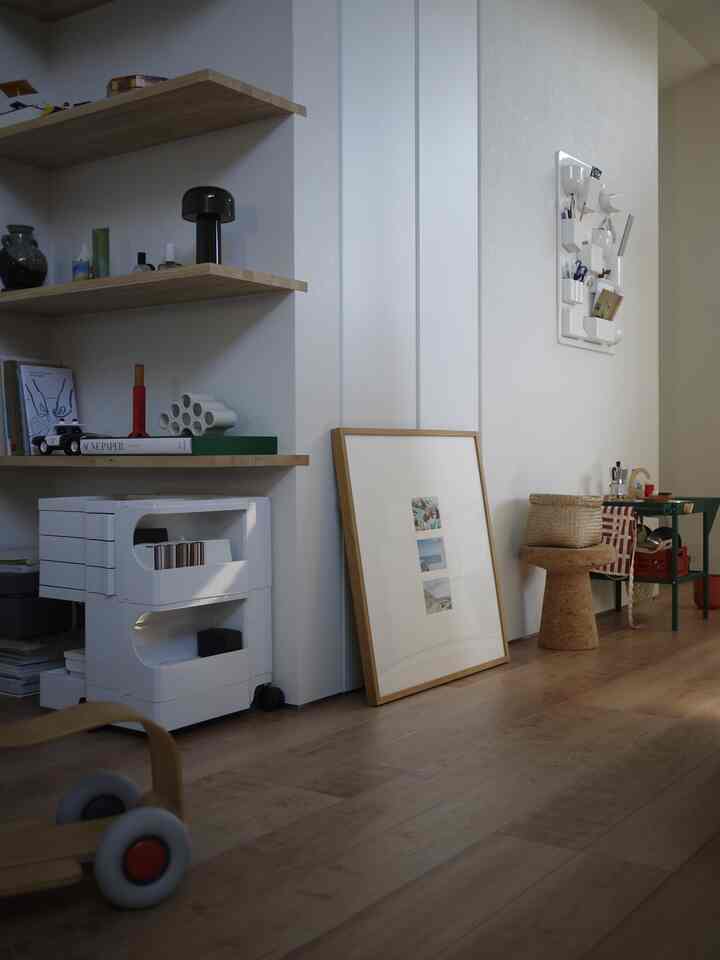 白い壁と木目調の床、木製の棚と収納棚が配置されたミニマルでナチュラルな雰囲気のリビングスペース