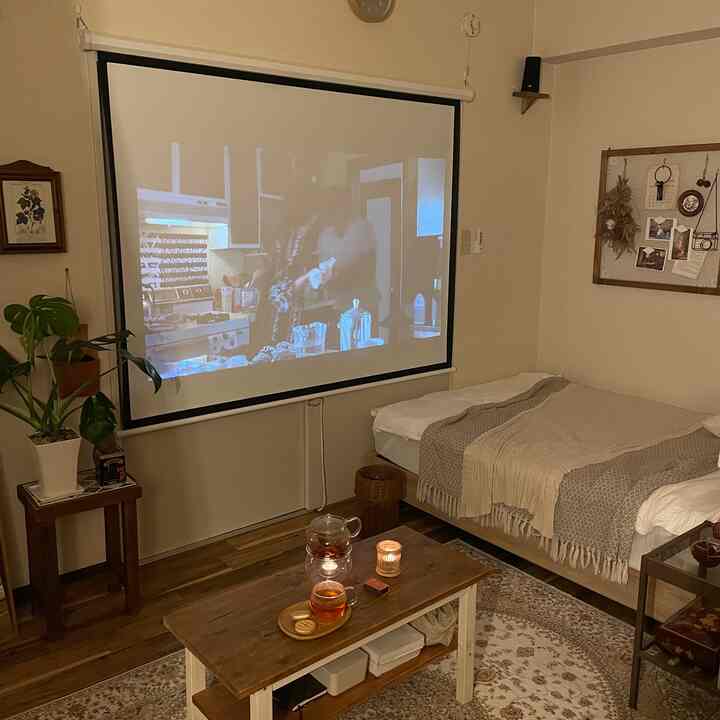 Cozy living room and home cinema space in warm wood tones and beige, featuring a bed, coffee table, and plants