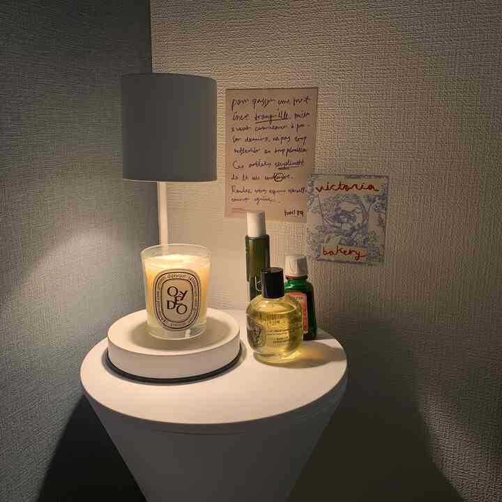 ホワイトトーンの寝室ナイトテーブルにキャンドルウォーマーとディフューザーが配置された雰囲気のあるインテリア