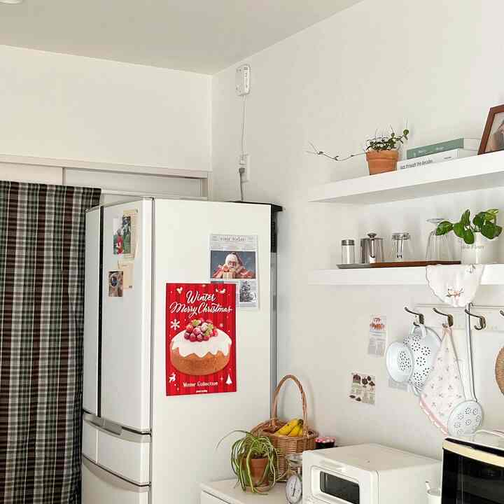White and natural toned kitchen featuring wall shelves and Christmas poster, creating a cozy holiday atmosphere