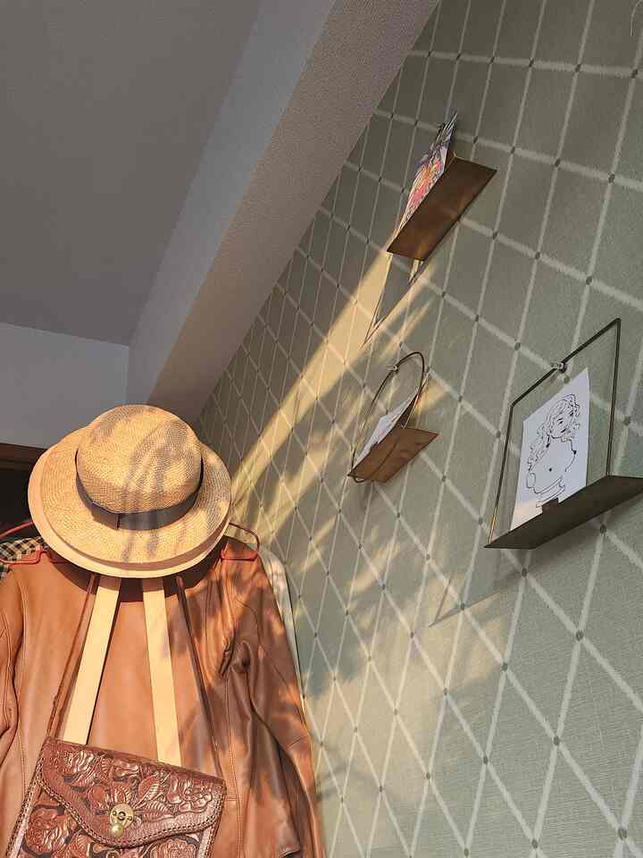 Beige checkered wall and brown leather coat, hat, and bag in an entrance space