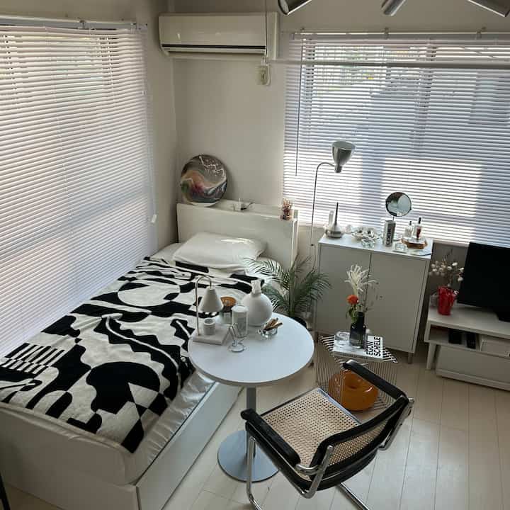 White and black toned single household bedroom featuring a neat layout, storage furniture, and natural elements