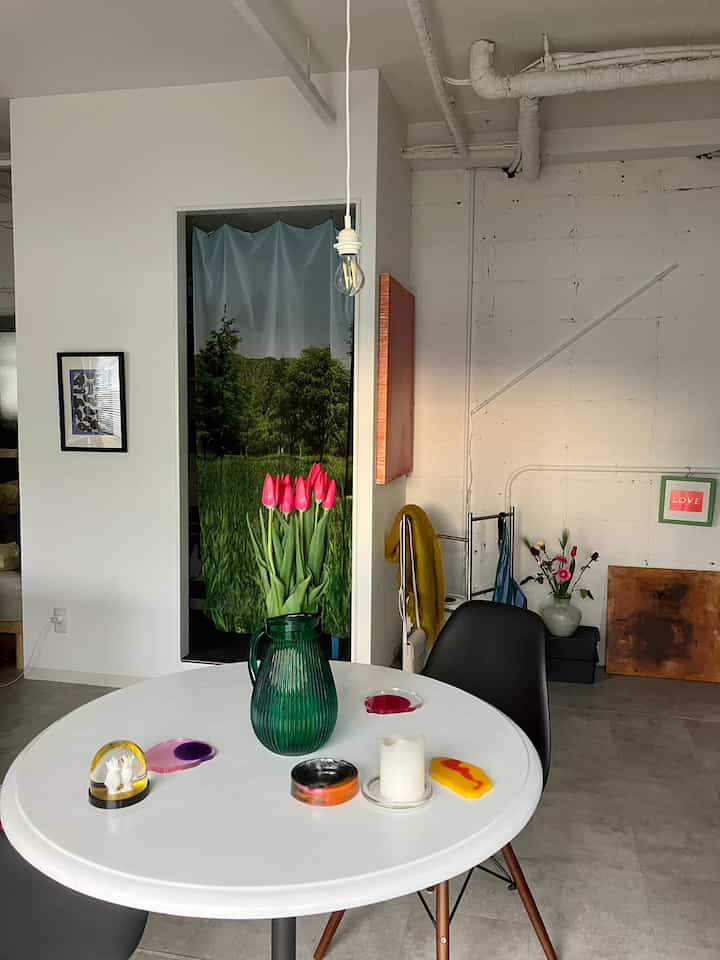 Modern white and gray studio apartment living room featuring round table with vase of bright red tulips, cozy and minimalistic atmosphere