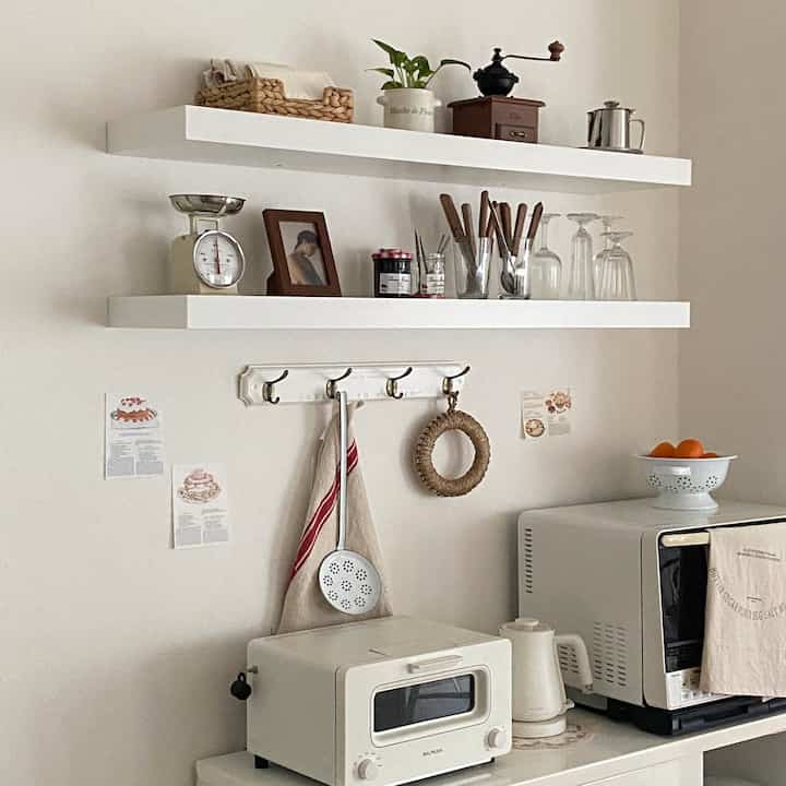 白とベージュのトーンのキッチン、壁に浮かぶ棚とキッチン家電が配置された雰囲気のあるインテリア