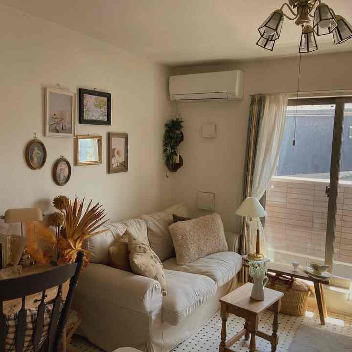 ナチュラルカラーのリビング、ホワイトのソファと額縁、バルコニーが配された雰囲気のあるインテリア