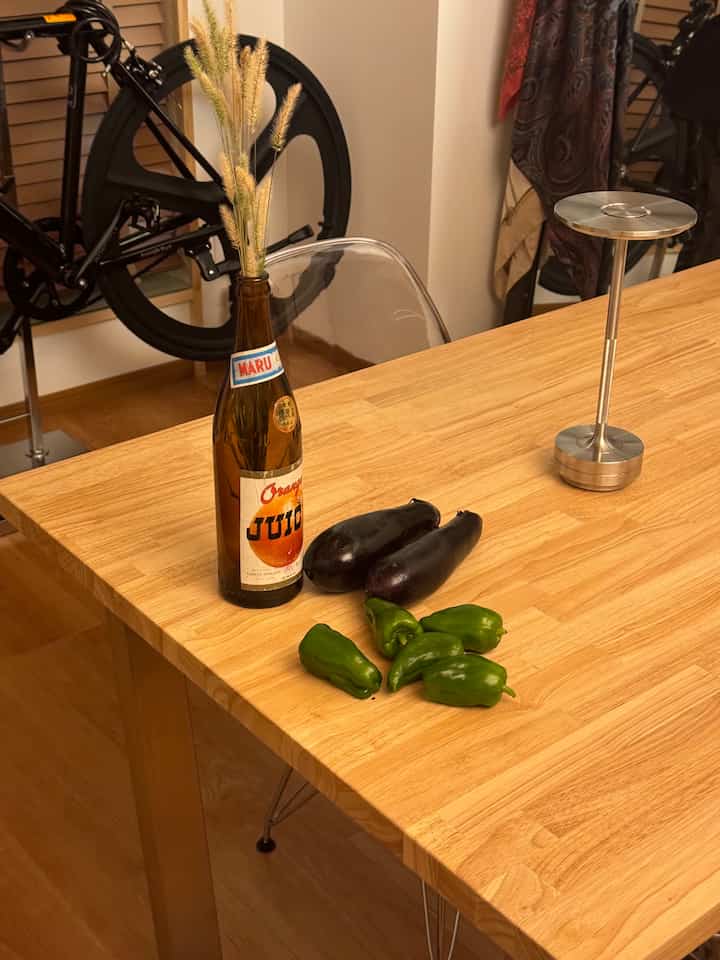 ナチュラルな木目調のダイニングルーム、透明な椅子と野菜が置かれたテーブルが配置された温かみのある空間