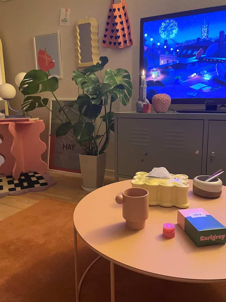 Cozy small living room with warm brown and pink tones, featuring a round tea table and a large green plant