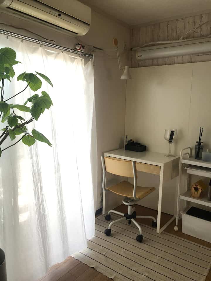 白と木目調のナチュラルなリビングのコーナー、デスクとオフィスチェアが配置された落ち着いたインテリア