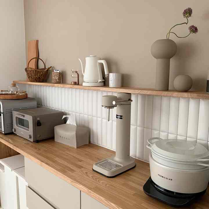 ベージュ色の壁と木目調の棚が配置されたキッチン空間、複数のキッチン家電とアロマオイルウォーマーが並ぶ清潔感のあるモダンなインテリア