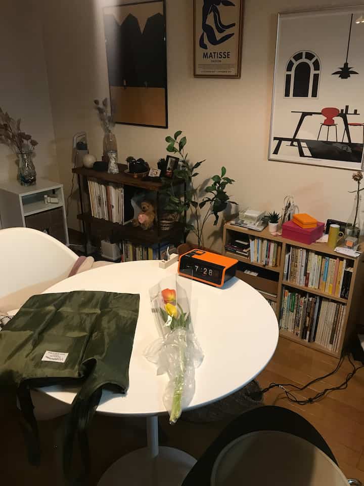 Natural cafe-style living room featuring a white round dining table and wooden shelves with plants and posters