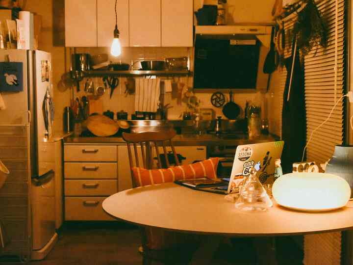 暖かいオレンジ色と白のトーンの小さなキッチン、円形のダイニングテーブルと椅子が配置された居心地の良いホームオフィス空間