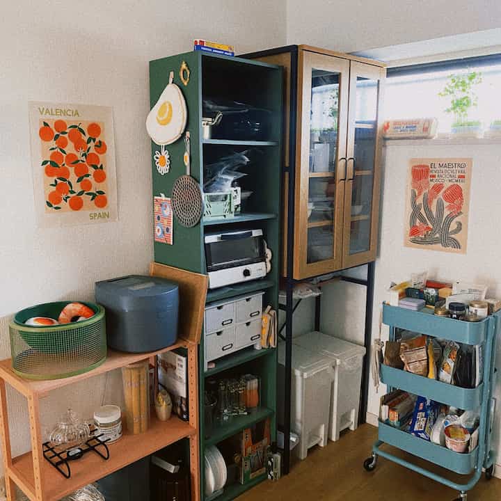 ナチュラルな木目調とグリーンの色調が調和するキッチン、収納家具とキッチンワゴンが配置された雰囲気のある空間