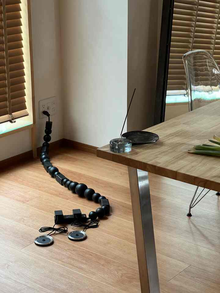 Wood tone floor and black cables near a kitchen table space, natural light and blinds harmonizing in a clean interior