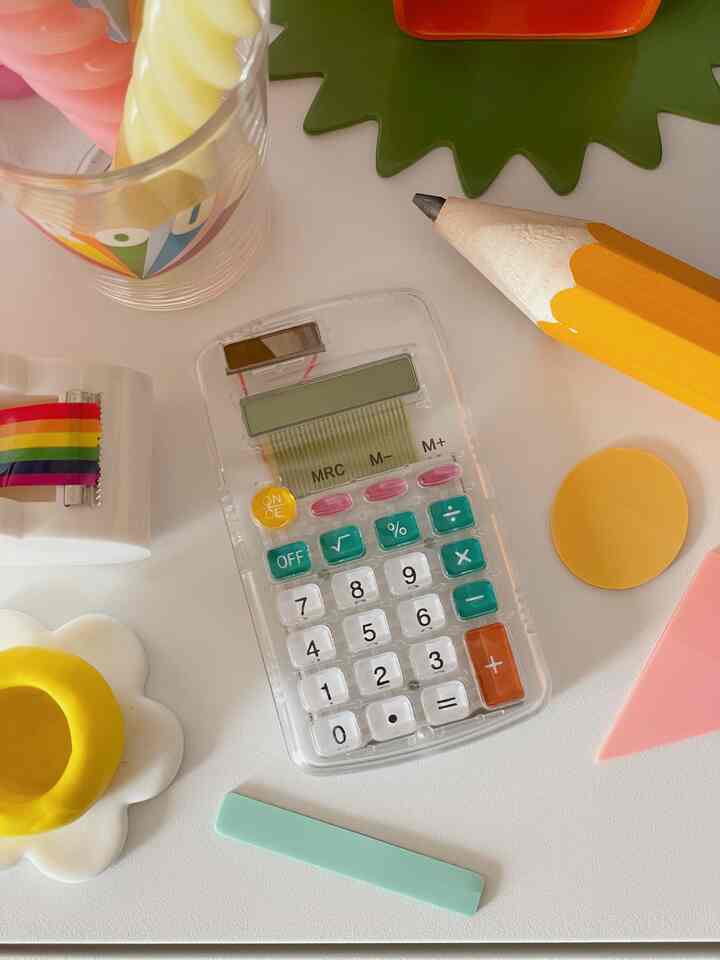 明るくカラフルな色調のテーブルに透明な電卓とかわいい装飾品が置かれたレトロな雰囲気のディスプレイコーナー