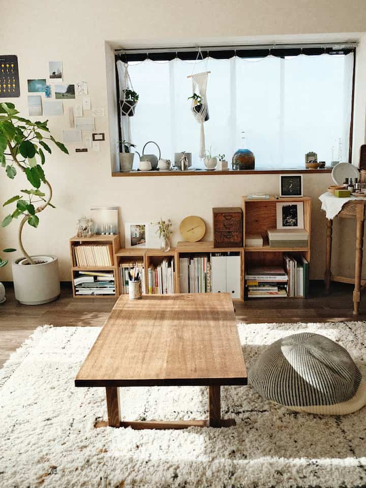 ナチュラルな木目調と白いラグが調和するリビング、自然光と植物が配されたシンプルなインテリア空間
