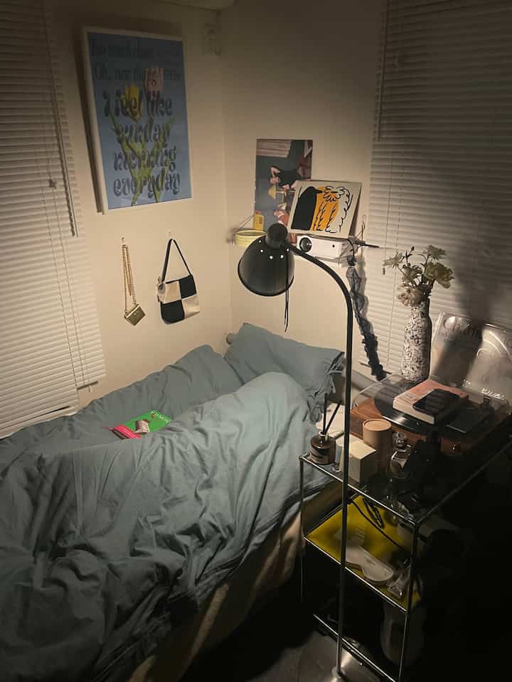 Cozy bedroom with wood tones and gray-blue bedding, featuring a reading lamp and book for a relaxing atmosphere