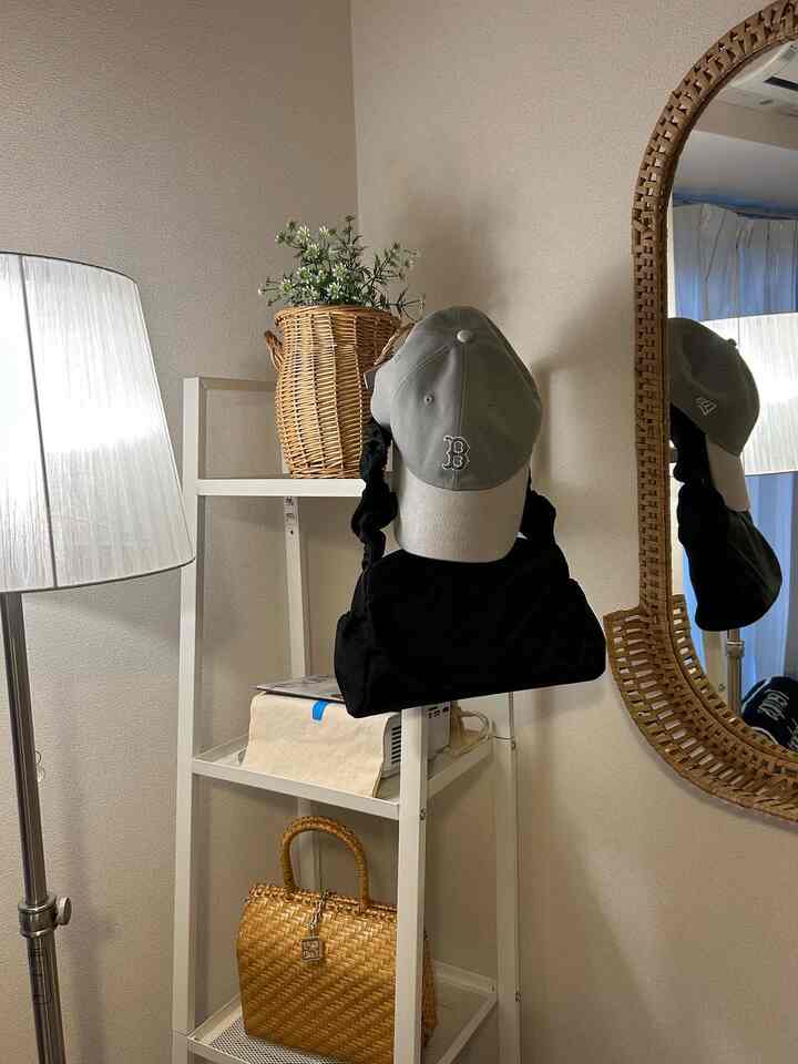 ホワイトのスリムシェルフとブラウンのラタン小物が配置されたナチュラルな印象の玄関空間