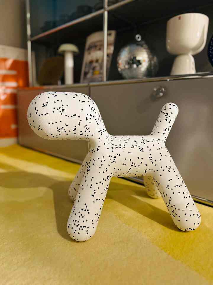 White dog-shaped objet with black spots placed in a warm orange-toned interior space