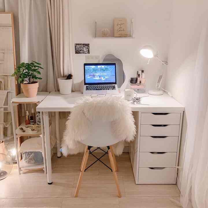 白とベージュのトーンでまとめられたシンプルで自然なホームオフィス、机と照明、植物が配置された雰囲気のあるインテリア