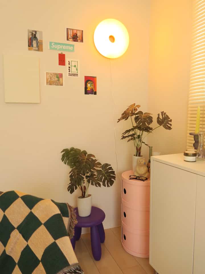 A cozy small room corner in warm white and pink tones, featuring colorful decor and storage units creating a charming atmosphere
