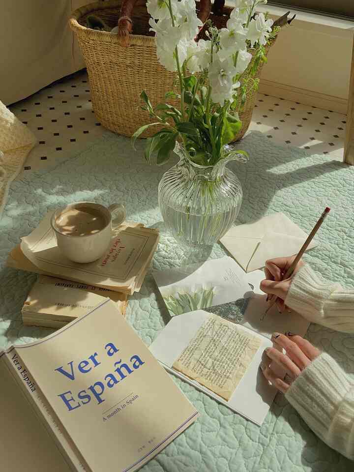 ナチュラルカラーのリビング、淡いグリーンのキルトカバーと透明な花瓶、コーヒーカップが配置された雰囲気のある空間