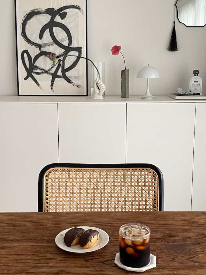 A simple home cafe style dining room with white walls and a natural wood tone table creating a cozy atmosphere