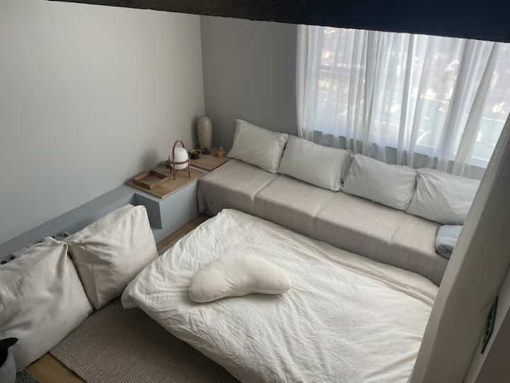 Bright living room in white and beige tones featuring a daybed and sofa, creating a cozy and airy atmosphere