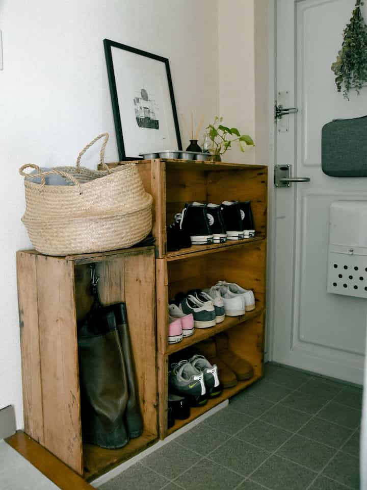 ナチュラルな木目調の玄関、ヴィンテージ感のある木箱の靴収納が配置された温かみのあるインテリア