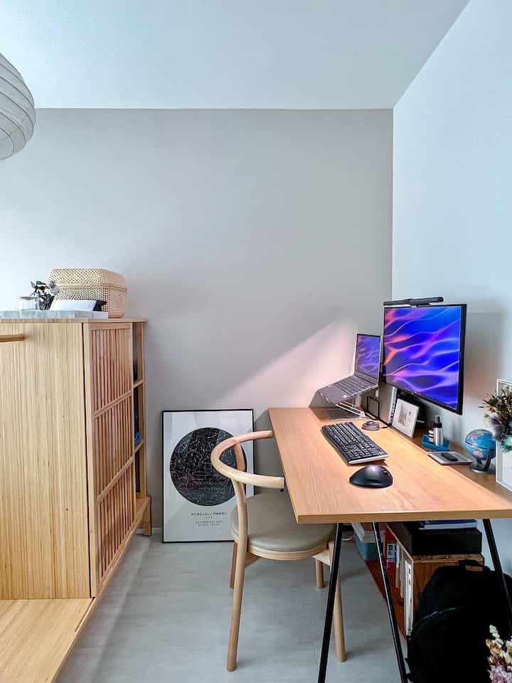 白とナチュラルウッド調のワークスペース、デスクの上にモニターとノートパソコンが配置された印象的なインテリア