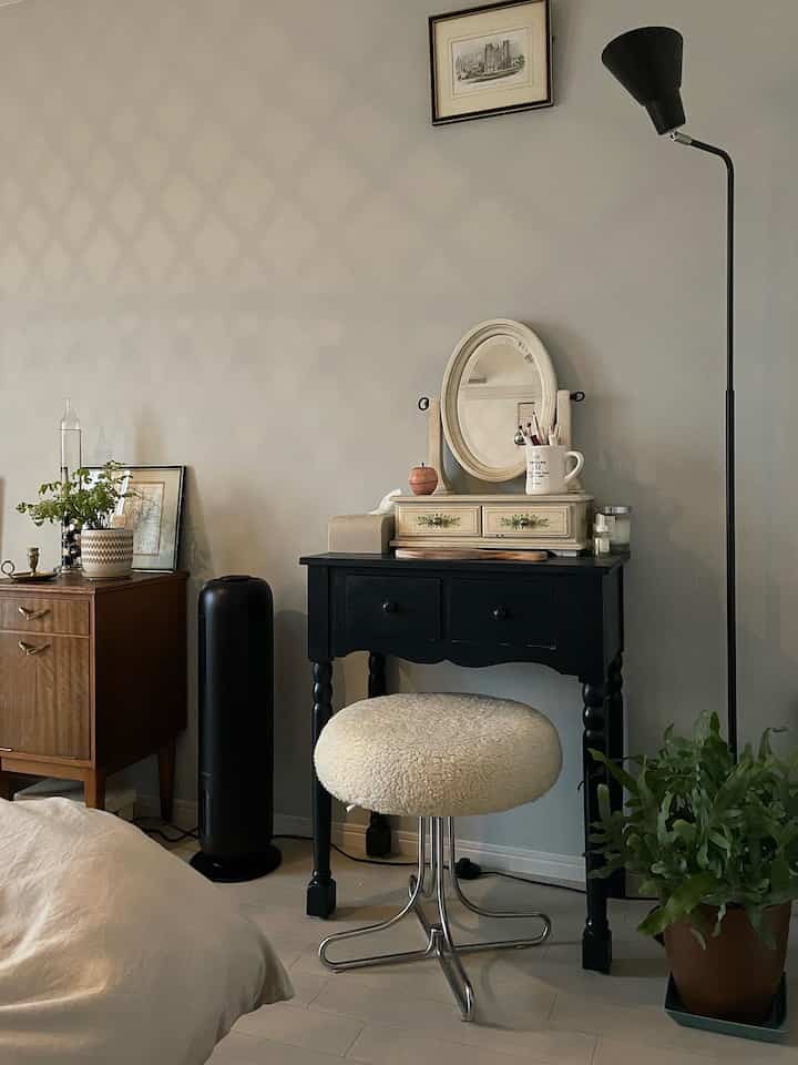 ネイビートーンの寝室にドレッサーとフロアランプ、プラントスタンドが配置された落ち着いた自然な雰囲気のインテリア