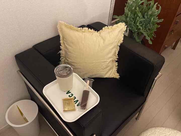 Living room with white walls and floor featuring a black armchair with beige cushion and decorative tray