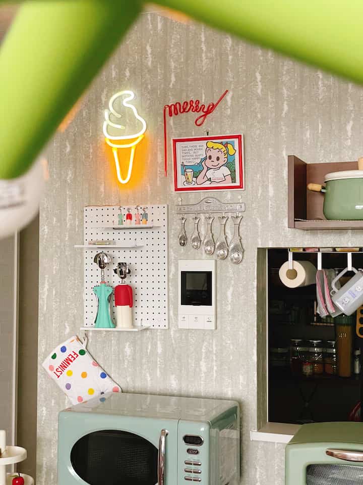 ミントカラーのキッチン空間、壁にネオンのアイスクリーム照明とレトロなポスターが配置されたアメリカンダイナー風インテリア
