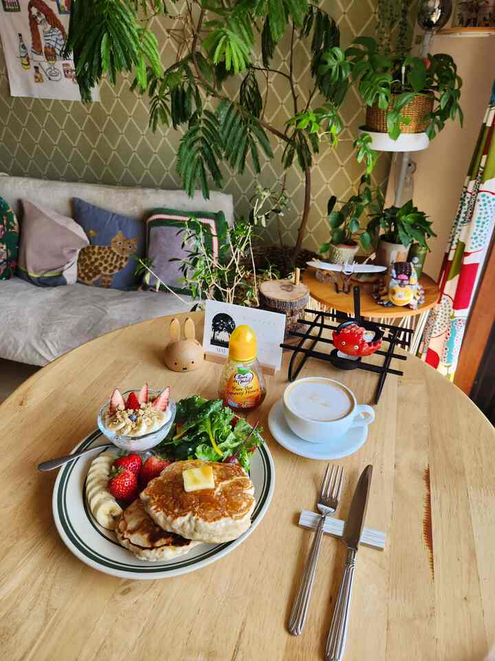 ナチュラルカラーのキッチンスペース、ダイニングテーブルとおうちカフェ風のコーヒーとパンケーキが置かれた雰囲気のある空間