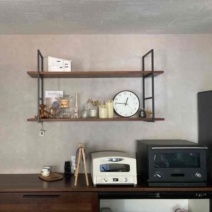Modern kitchen in wood tones and black, featuring shelves with coffee accessories and clock, creating a cozy home cafe vibe
