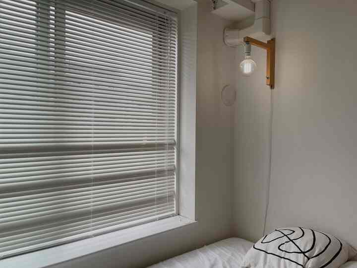 White and natural toned bedroom featuring two large beds and blinds in a simple, neat space