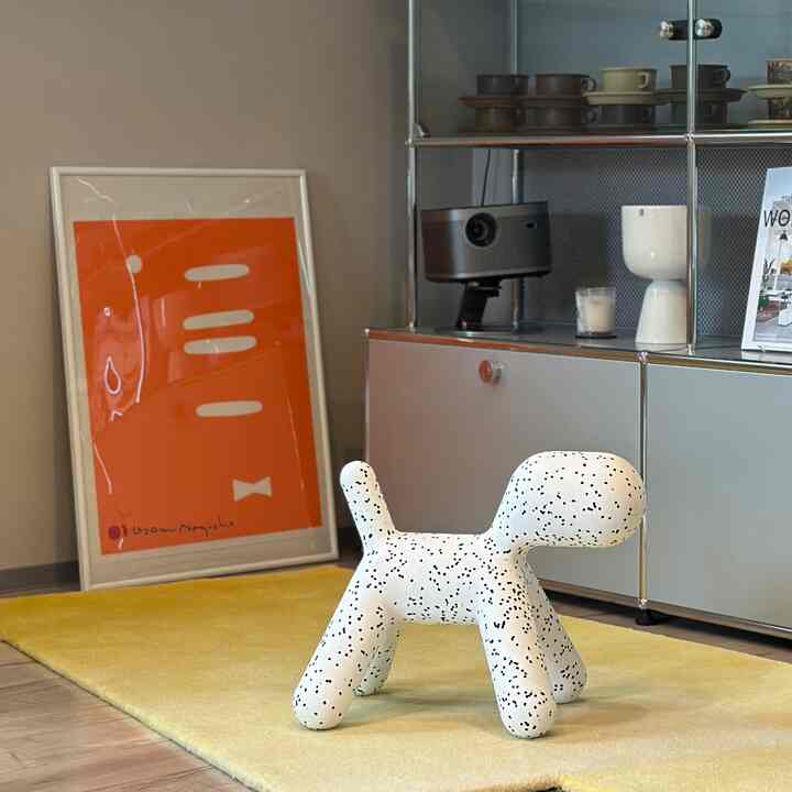 Modern living room with warm yellow rug and vibrant orange poster, featuring a white pet-shaped decor in center