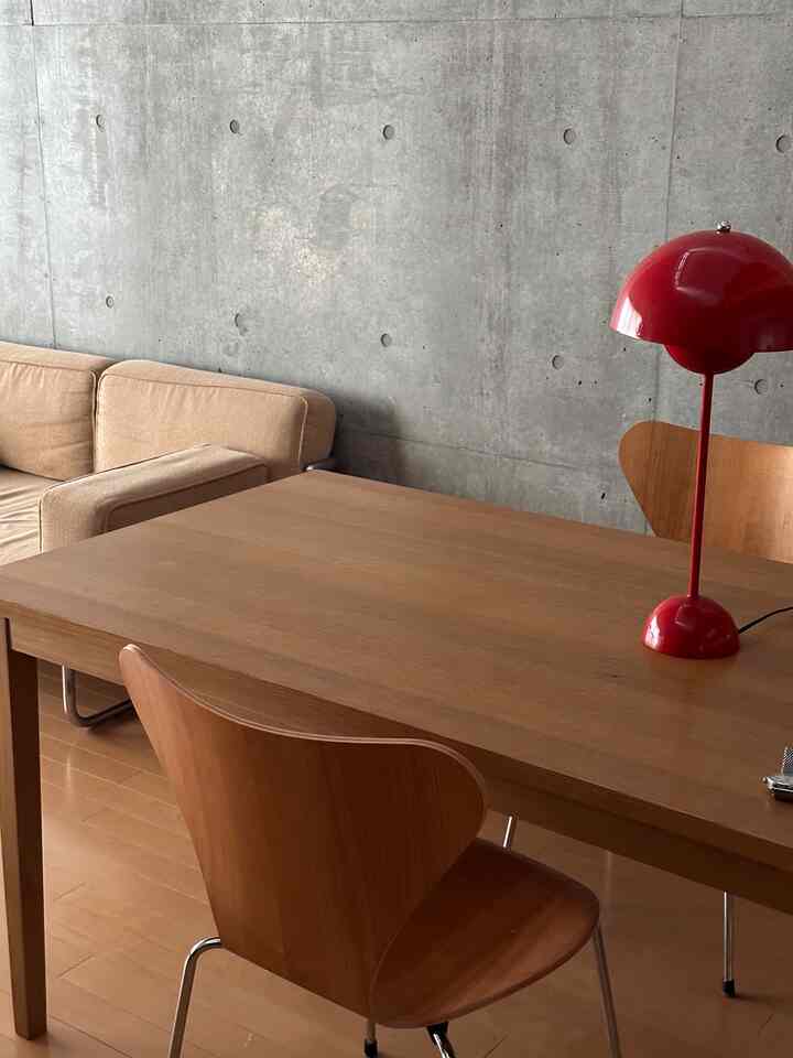 A simple kitchen space blending natural wood tones and concrete wall, featuring a wooden dining table and chairs