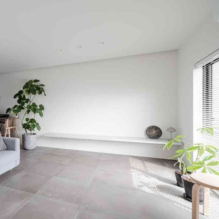 Gray and white toned living room featuring 600x600 tiles floor and plants with a simple, spacious atmosphere
