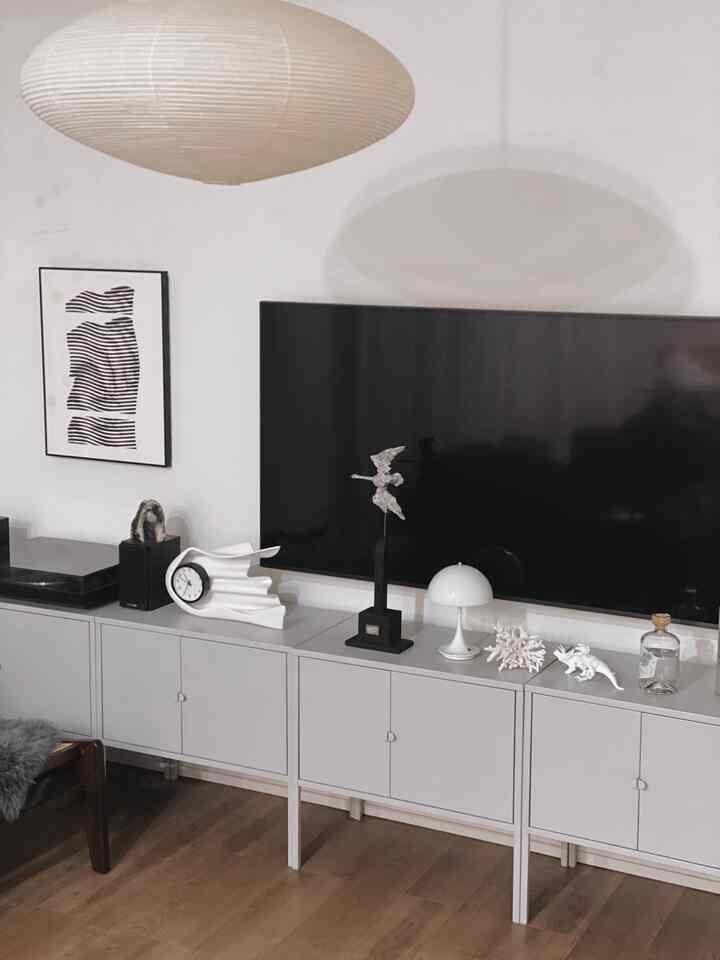 モノトーンで白を基調としたリビング、テレビ台の上にテーブルランプやオブジェが配置されたシンプルモダンなインテリア