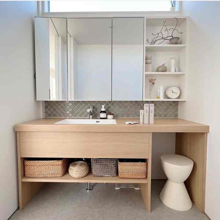 ナチュラルカラーとホワイトトーンのホテルライクなバスルームの化粧台、ラタン収納が配置された清潔感のある印象的な空間