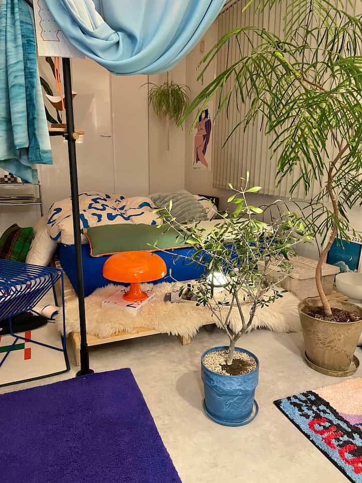 ナチュラルな色調の寝室、パレット風ベッドとブルーやウッドトーンの要素、植物が調和した居心地の良い空間