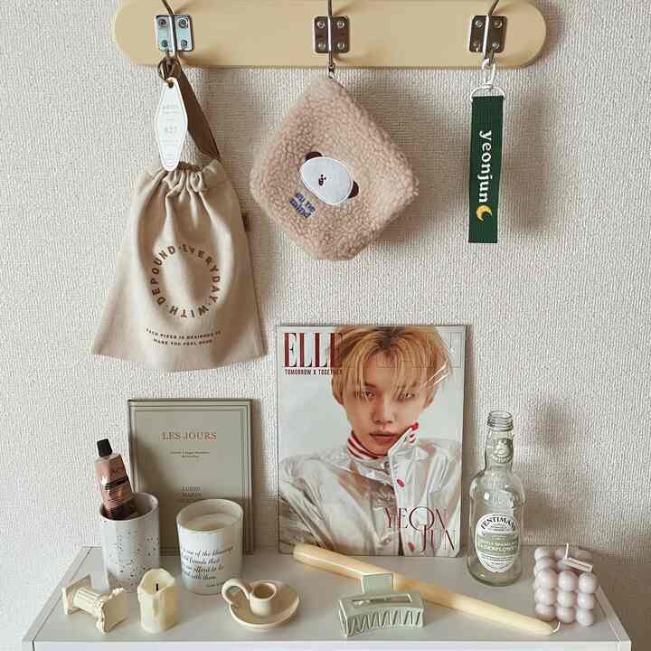 クリーム色の壁とホワイトの棚にミニマルなキャンドル、額縁、小さなオブジェが配置されたナチュラルトーンの壁飾りのあるインテリア