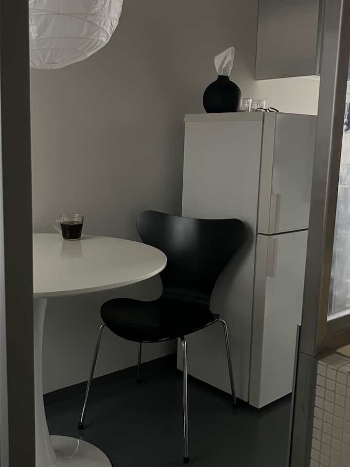 Monotone dining space in white and black featuring a round dining table and black dining chair in a compact kitchen area